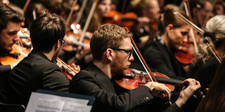 Studentenorchester der TU Dortmund Ein Musiker mit Geige des Studentenorchesters der TU Dortmund im Fokus