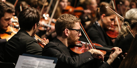 Studentenorchester der TU Dortmund Ein Musiker mit Geige des Studentenorchesters der TU Dortmund im Fokus