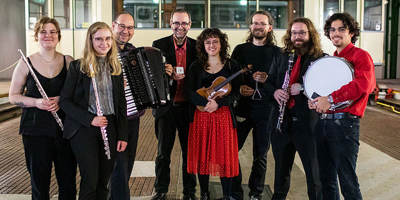Das Ensemble für Neue Kammermusik Ein Gruppenfoto des Ensemble für neue Kammermusik. Alle Musiker:innen halten ihre Instrumente im Arm.