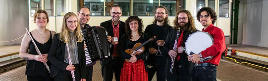Das Ensemble für Neue Kammermusik Ein Gruppenfoto des Ensemble für neue Kammermusik. Alle Musiker:innen halten ihre Instrumente im Arm.