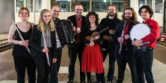 Ein Gruppenfoto des Ensemble für neue Kammermusik. Alle Musiker:innen halten ihre Instrumente im Arm.