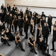 Ein Gruppenfoto vom Kammerchor der TU Dortmund. Die schwarz gekleideten Musiker*innen sind von halboben fotografiert.
