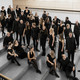 Der Kammerchor der TU Dortmund Ein Gruppenfoto vom Kammerchor der TU Dortmund. Die schwarz gekleideten Musiker*innen sind von halboben fotografiert.