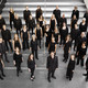 Ein Gruppenfoto vom Kammerchor der TU Dortmund. Die schwarz gekleideten Musiker*innen sind von oben fotografiert.