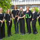 Gruppenbild des Ensembles "TU Flutes", die Musiker*innen halten ihre Flöten in der Hand, die Leiterin hält ein grünes TU-Logo in der Hand.