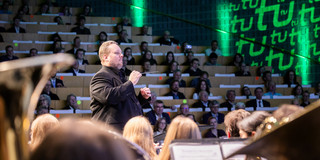 Der Dirigent des Sinfonischen Blasorchesters, Constantin Hesselmann, dirigiert das Orchester während eines Konzertes.